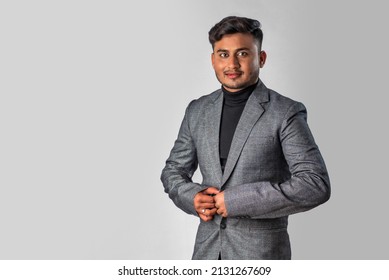 Portrait of Happy Indian young man, businessman wearing a blazer on grey background posing, satisfied successful male in formal suit