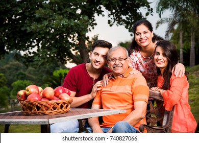 Portrait Of Happy Indian/Asian Family While Sitting On Lawn Chair, Outdoor
