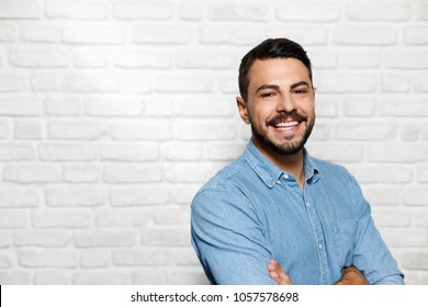 Portrait Of Happy Italian Man Smiling Against White Wall As Background And Looking At Camera.