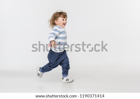 Portrait of happy joyful running beautiful little boy, studio shot on white