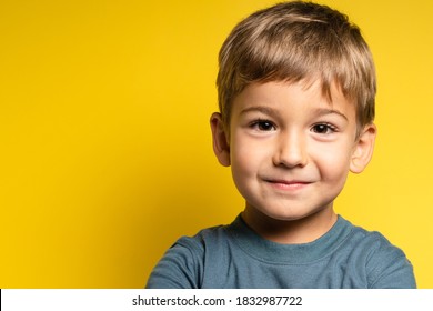 Portrait of happy joyful small caucasian boy in front of yellow background looking to the camera - Childhood growing up and concept - front view waist up copy space