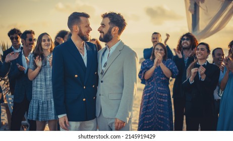 Portrait Of A Happy Just Married Handsome Gay Couple Kissing. Two Attractive Queer Men In Suits Smile And Pose For Camera With Diverse Friends. LGBTQ Relationship And Family Goals.