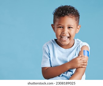 Portrait, happy and kid with plaster in studio isolated on a blue background mockup space. Face, smile and boy child with bandage after vaccine, injury or wound for healthcare, first aid and excited.