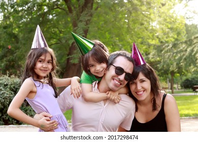 Portrait Of Happy Latin Family Looking At Camera With Birthday Hats