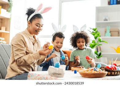 Portrait happy latin family wearing bunny ears painting eggs preparation together for Easter holiday  - Powered by Shutterstock