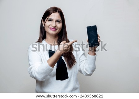portrait of happy latin indian female pointing towards the phone and looking towards the camera