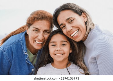 Portrait of happy latin multigenerational family smiling on camera - Grandmother, mother and child having fun together outdoor - Powered by Shutterstock