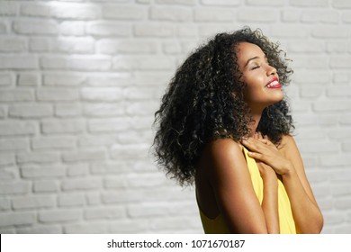 Portrait of happy latina woman smiling and saying prayer. Black girl looking up while praying.