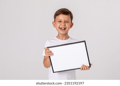 portrait happy laughing baby boy holding white drawing Board white background  young boy is holding drawing board in her hands  white isolated background  Mock up  Copyspace 