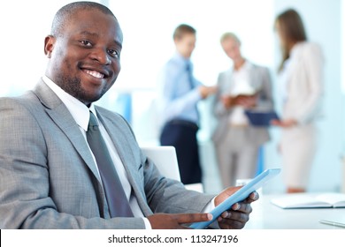 Portrait Of Happy Leader With Touchpad Looking At Camera In Working Environment