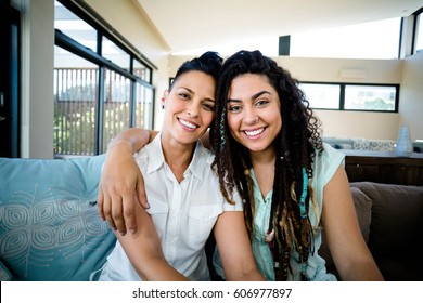 Portrait of happy lesbian couple embracing each other and smiling in living room - Powered by Shutterstock