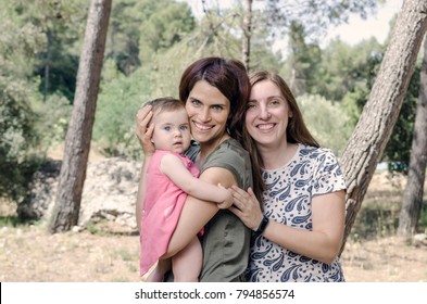 Portrait Of Happy Lesbians Mothers With A Baby.  Homosexual Family In A Countryside