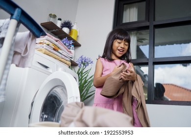 Portrait Of Happy Little Asian Girl Doing Laundry At Home