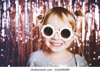 Portrait Of Happy Little Girl In Dress And Sunglasses Having Fun On The Festive Background. Kids Birthday Or Fancy Dress Party, Disco Music Or New Year. Celebration And Holiday Concept.