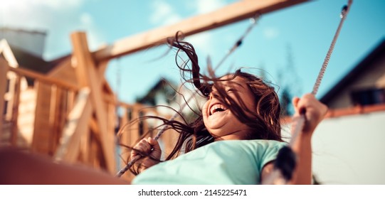 Portrait of a happy little girl sitting on a swing and smiling - Powered by Shutterstock