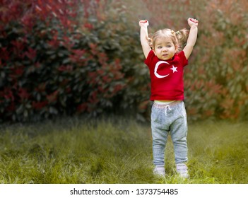 Portrait Of Happy Little Kid, Cute Baby Toddler With Turkish Flag T-shirt Wave Her Hand. Patriotic Holiday. Adorable Child Celebrates National Holidays. Blur Background With Copy Space For Text.