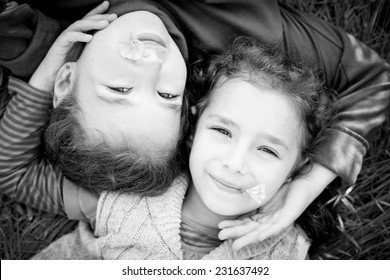 Portrait Of Happy Little Sister Lying On The Grass ( Black And White )