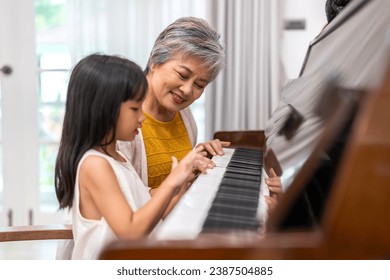 Portrait of happy love asian grandmother and asian cute girl play and enjoy relax teaching and play piano music lesson at home.senior, insurance, care.girl with their laughing grandparents.Family	 - Powered by Shutterstock