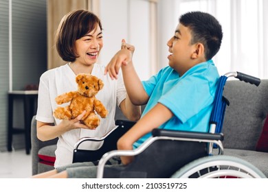 Portrait of happy love family asian mother play and helping look at disabled son child sitting in wheelchair at home.disability care concept