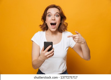 Portrait of a happy lovely girl standing isolated over yellow background, using mobile phone, celebrating - Shutterstock ID 1377275717