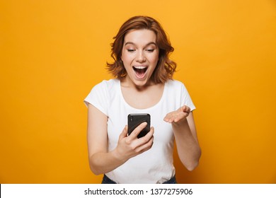 Portrait of a happy lovely girl standing isolated over yellow background, using mobile phone, celebrating - Shutterstock ID 1377275906