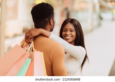 Portrait Of Happy Loving African American Woman Embracing Her Man, Carrying Shopping Bags And Looking At Camera, Black Couple Black Couple Hugging, Shopping In Modern Mall, Blurred Background