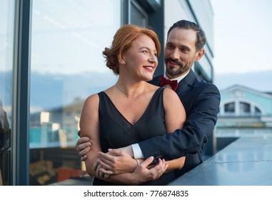 Portrait of happy loving couple standing on balcony and hugging. They are smiling with joy - Shutterstock ID 776874835