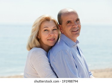 Portrait of happy loving mature couple against sea in background 