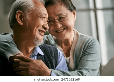 portrait of happy loving senior asian couple sitting on couch at home - Powered by Shutterstock