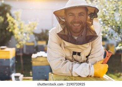 Portrait of a happy male beekeeper working in an apiary near beehives with bees. Collect honey. Beekeeper on apiary. Beekeeping concept. - Powered by Shutterstock