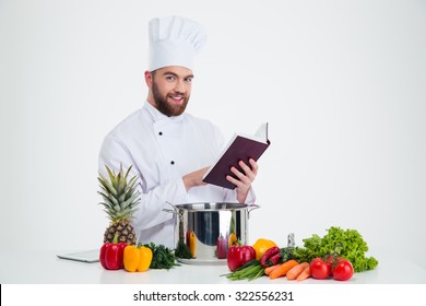 Portrait Of A Happy Male Chef Cook Holding Recipe Book And Preparing Food Isolated On A White Background