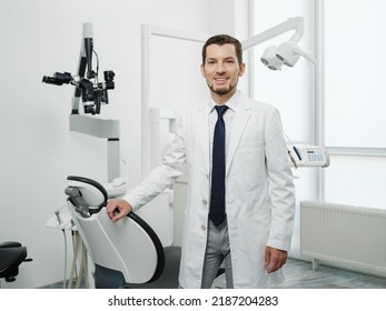 Portrait Of Happy Male Dentist Wearing Lab Coat In White Dental Clinic