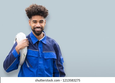 Portrait Of A Happy Male Electrician With Cable Coil On Gray Background