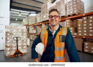 Portrait Of A Happy Male Employee At Manufacturing Industry With Stacked Of Cardboard Boxes