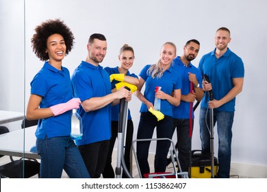 Portrait Of Happy Male And Female Janitors With Cleaning Equipment