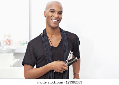 Portrait Of Happy Male Stylist Holding Hairbrush And Scissors