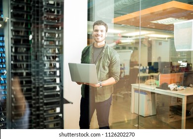 Portrait Of Happy Male Technician With Laptop In Large Data Center