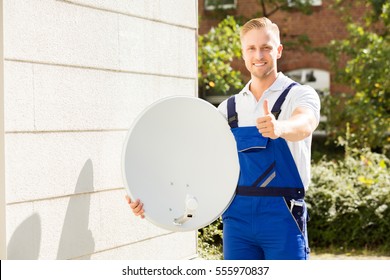 Portrait Of A Happy Male Technician With TV Satellite Dish Gesturing Thumbs Up