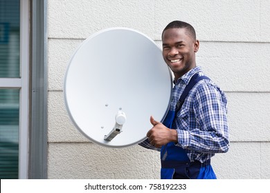 Portrait Of A Happy Male Technician With TV Satellite Dish Gesturing Thumbs Up