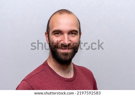 Portrait of a happy man 30-35 years old, bald and with a beard on a light background.