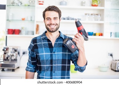 Portrait of happy man holding with drill machine in kitchen at home - Powered by Shutterstock