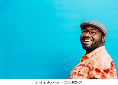 Portrait of a happy man in orange shirt looking up, with blue copy space around him