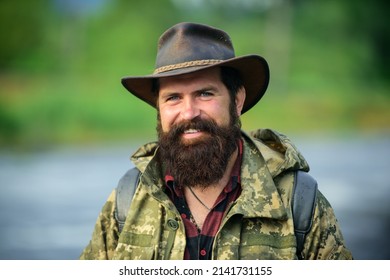 Portrait Of Happy Man Traveler With Backpack Hiking Outdoor. Travel Lifestyle Countryside And Adventure Concept. Portrait Smiling Traveller Bearded Man In Cowboy Hat.