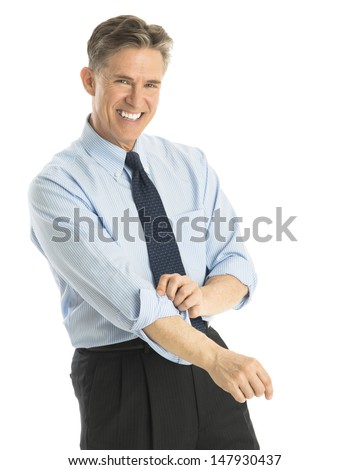 Portrait of happy mature businessman rolling up his sleeves while standing against white background