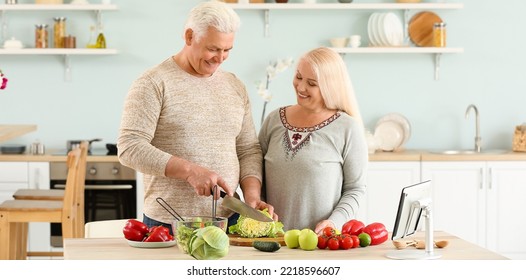 Portrait Of Happy Mature Couple Cooking In Kitchen