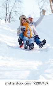 Portrait Of Happy Mature Couple Riding On Sledge In Winter