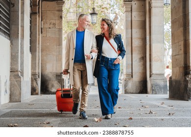 Portrait of a happy mature couple sightseeing on a romantic journey trip in Spain. Middle aged married people walking with a suitcase. Wife and husband smiling and having fun on a weekend tour. High - Powered by Shutterstock