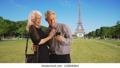 Portrait Of Happy Mature Couple Using Smartphone In Paris