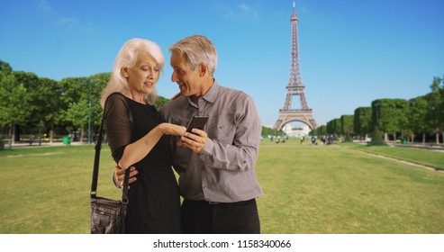 Portrait Of Happy Mature Couple Using Smartphone In Paris