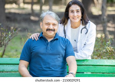 Portrait Of Happy Mature Female Indian Doctor Wearing Apron And Senior Male Patient Outdoor In The Park, Healthcare Profession.